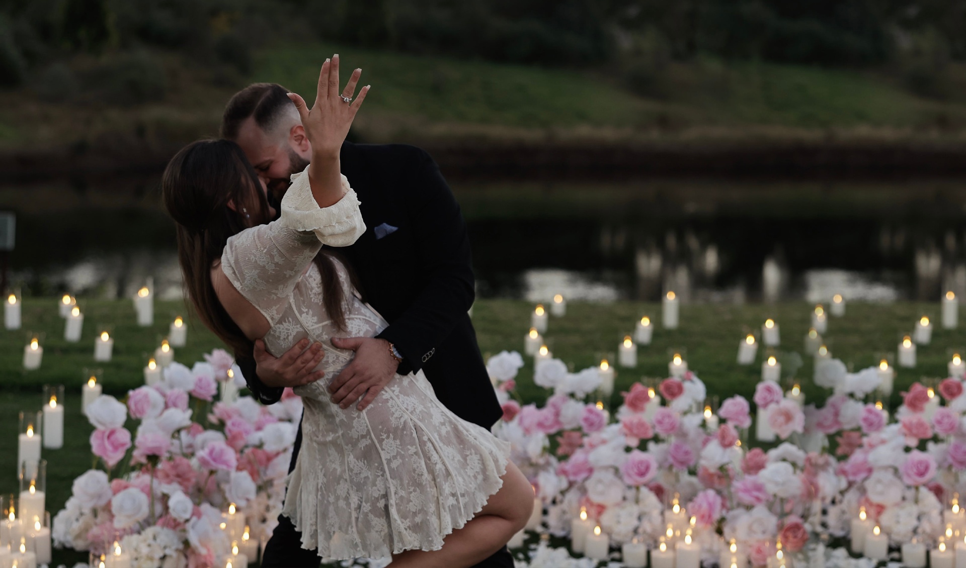 Romantic proposal moment with couple embracing surrounded by candles and flowers